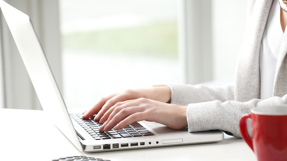 Person typing on a laptop with a bright background.