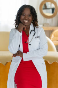 A smiling female doctor in a white coat and red dress.