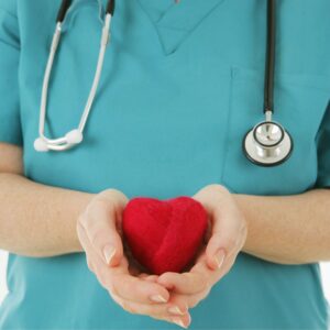 Healthcare worker holding a red heart symbolizing care and compassion.
