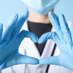 Person wearing blue gloves forming a heart shape with hands.